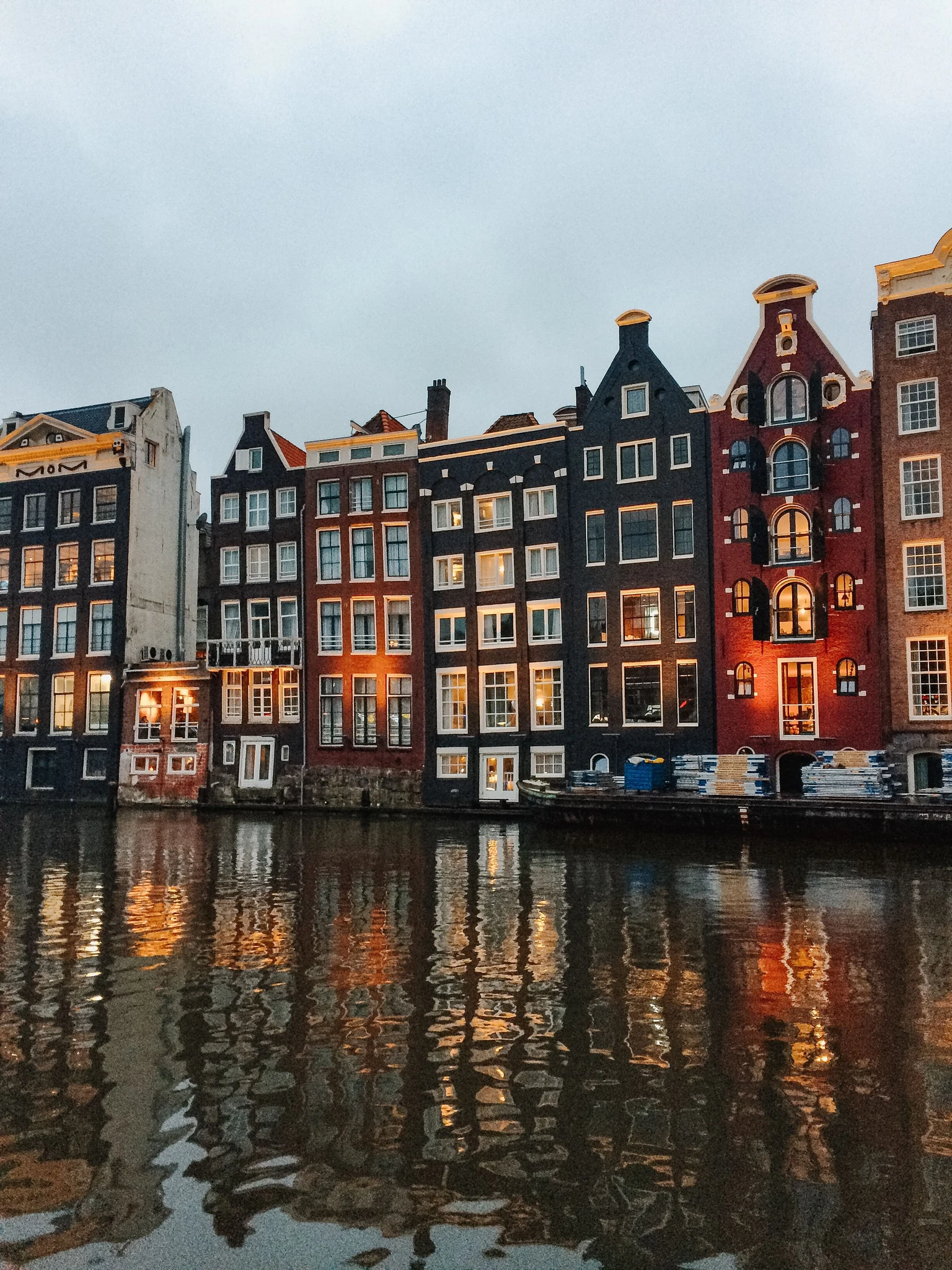 Canal houses and their lights reflected in the water at dusk.