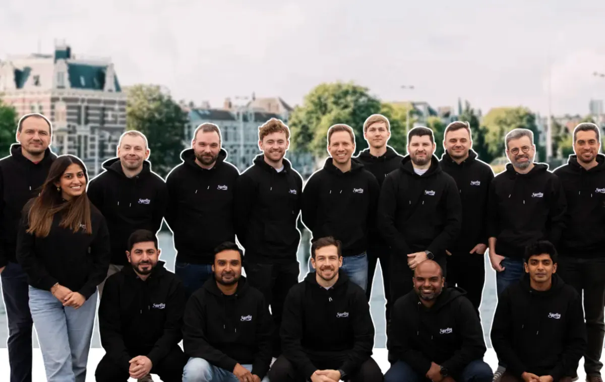 A large group of people in Surfly-branded hoodies pose together outdoors.